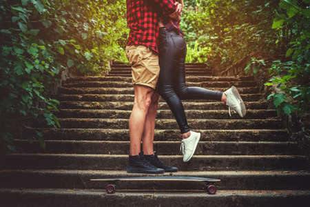 Casual moder young skateboarders couple posing on footway in a forest park.の写真素材