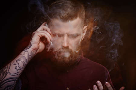 Bearded male with tattoo on his arm speaking by smartphone.の写真素材