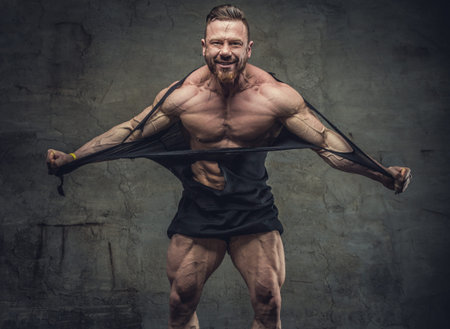 Huge bodybuilder rend his garments. Studio shoot.