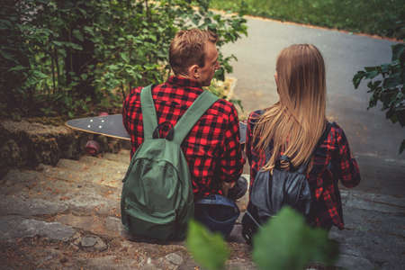 Male in a red shirt with longboard relaxing with his girlfriend on stairway in a park.の写真素材