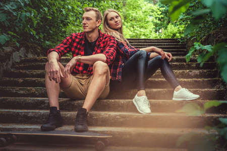 Casual moder young skateboarders couple posing on footway in a forest park.の写真素材