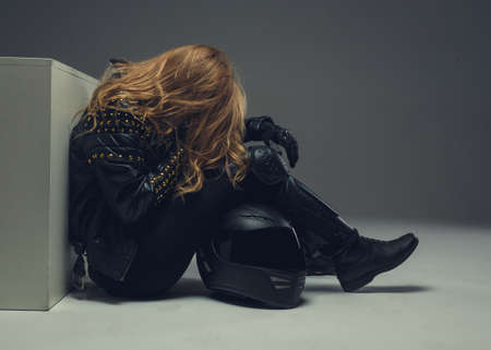 Portrait of blond female in motorcycle uniforme with moto helmet.の写真素材