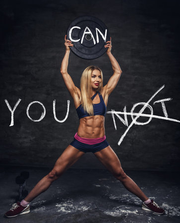Attractive female fitness model posing with barbell weight on a grey backgorund. Motivational poster.の写真素材