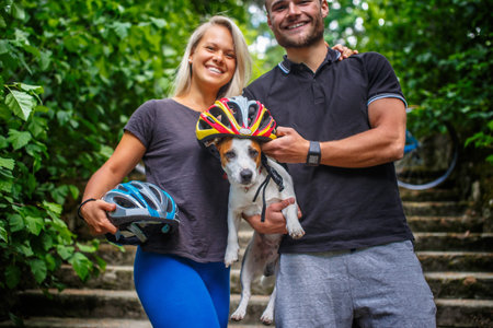 Sporty couple posing with ther dog after bycicle riding in a forest.