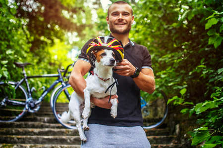 Ciclist male posing with his russel dog on stairs in a forest.の写真素材