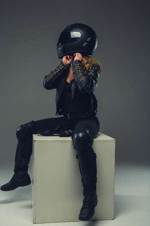 Female in leather clothes and safety helmet on a grey background.の写真素材