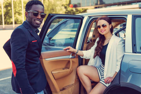 Meeting of black casual man and caucasiand business woman near a car.の写真素材