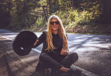 Blond female in sunglasses sitting on a road in a wood.の写真素材