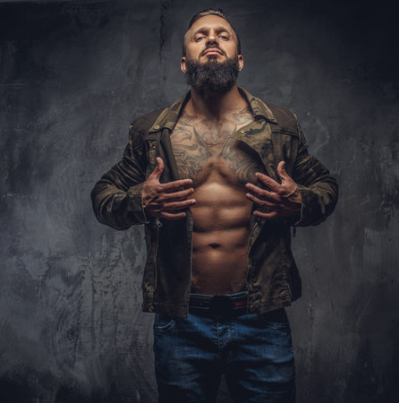 Portrait of modern bearded male in denim jeans and casual jacket dressed on naked torso.