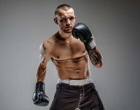 Agressive tattooed fighter isolated on a grey background.の写真素材