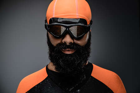 Close up portrait of bearded male in scuba diving mask and orange neopren diving suit isolated on grey background.の写真素材