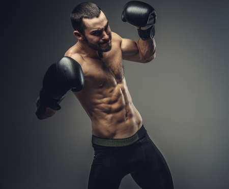 Studio portrait of shirtless male fighter in boxing gloves.の写真素材