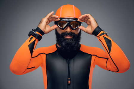 Portrait of bearded male in scuba diving mask and orange neopren diving suit isolated on grey background.の写真素材