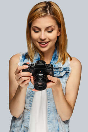 Portrait of blond female photographer isolated on grey background.