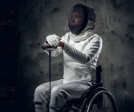 Female fencer in wheelchair with safety mask on a face.
