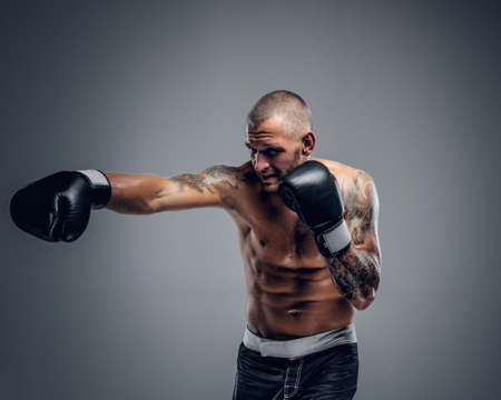 Studio portrait of the shirtless boxing fighter isolated on grey background.の写真素材
