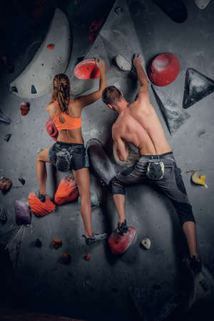 Sporty male and female climbing on an indoor climbing wall.の写真素材