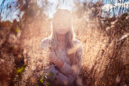 Portrait of blond female in sunglasses in a field on a sunset.の写真素材