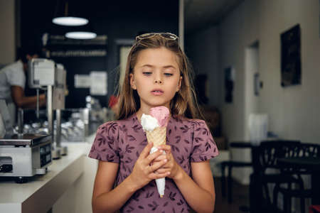 Young pretty girl in a dress, eating ice cream in a cafe.の写真素材