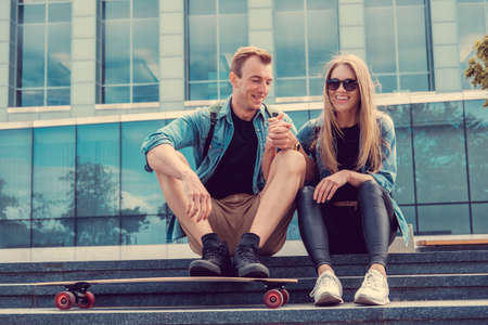 Gentle urban couple relaxing on stairs after longboard riding in a city.の写真素材