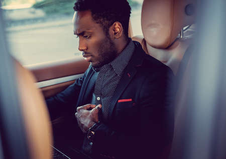 Portrait of luxury African male using laptop in a car.の写真素材