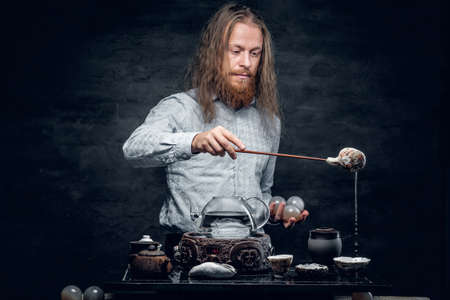 Positive bearded male pours hot water in a tea ceremony.の写真素材
