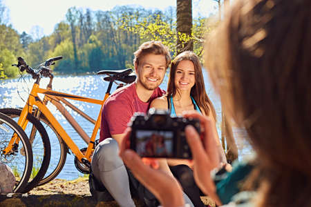 A woman taking pictures of sporty couple after bicycle ride in a forest.