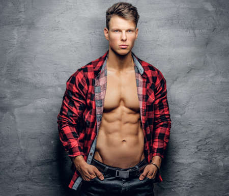 Fashionable abdominal male in a red shirt on grey background.の写真素材