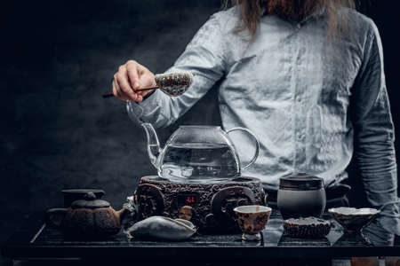 Positive bearded male pours hot water in a tea ceremony.の写真素材