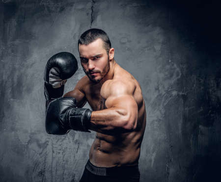 Aggressive shirtless boxer on grey background.