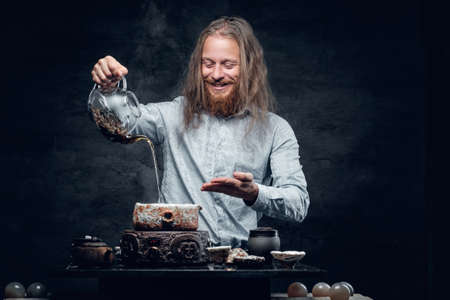 Positive bearded male pours hot water in a tea ceremony.の写真素材