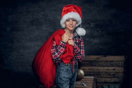 Cute teenage boy in Santa's hat holds New Year gift sack.の写真素材