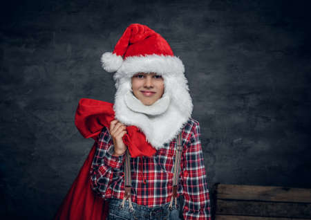 Cute teenage boy in Santa's hat holds New Year gift sack.の写真素材