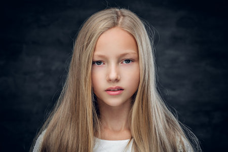 Studio portrait of blonde teenage girl on grey background.の写真素材