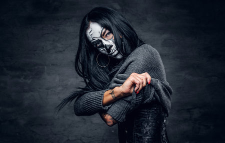Female with skull make up undressing on dark background.の写真素材