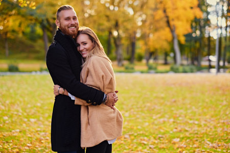 Autumn love story. Attractive redhead male hugs cute blonde female in autumn wild nature background.の写真素材