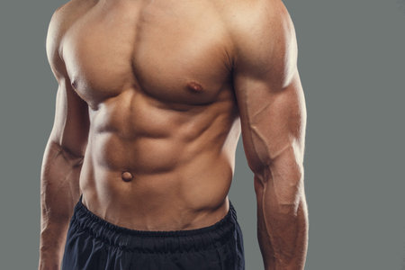 Athletic male's body with grey background.