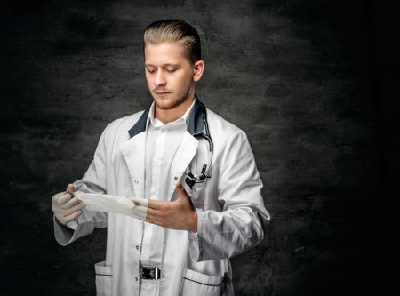 Portrait of confident young medical doctor on grey background.