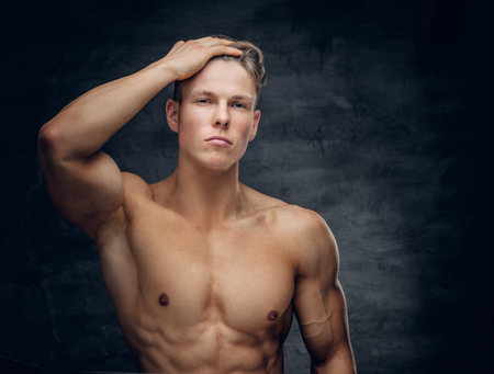 Portrait of sensual shirtless athletic male on grey background.