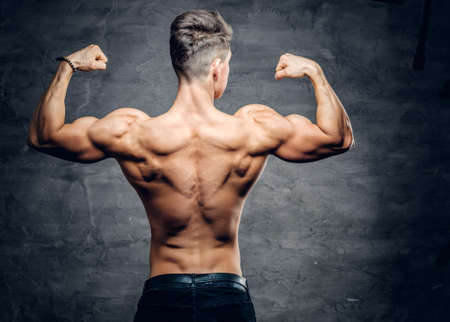 Athletic shirtless man from the back on grey background.の写真素材