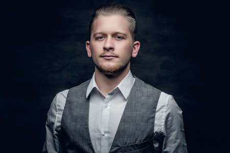 Studio portrait of young businessman in white sleeveless shirt on dark grey background.の写真素材