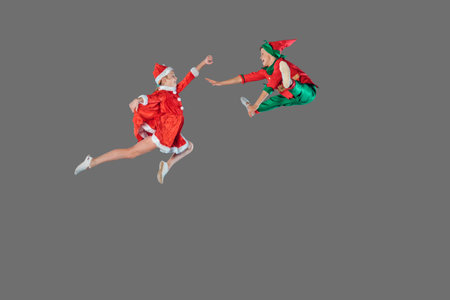 Jumping funny kids in Peter pan and snow maiden costume isolated on grey background.の写真素材