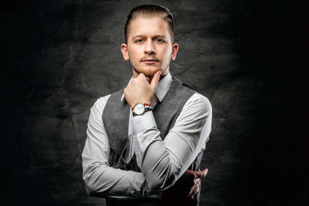 Studio portrait of young businessman in white sleeveless shirt on dark grey background.の写真素材