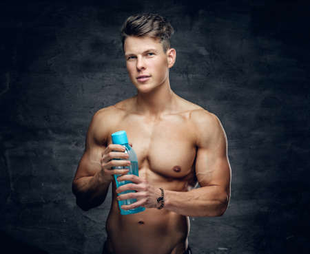 The attractive shirtless muscular guy holds a bottle of water.の写真素材