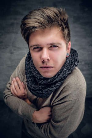 Funny studio portrait of a man in autumn pullover and scarf on grey background.の写真素材