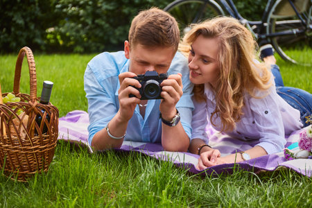 Loving young couple photo shooting and relaxing at a picnic in a park.