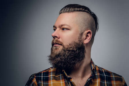 Portrait of a bearded hipster male with punk hairstyle dressed in a yellow shirt on grey background.の写真素材