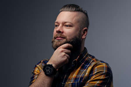 Portrait of a bearded hipster male with punk hairstyle dressed in a yellow shirt on grey background.の写真素材