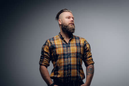 Portrait of a bearded hipster male with punk hairstyle dressed in a yellow shirt on grey background.の写真素材