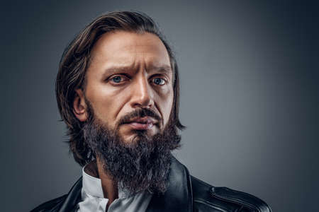 Close up studio portrait of serious, bearded male on grey background.の写真素材